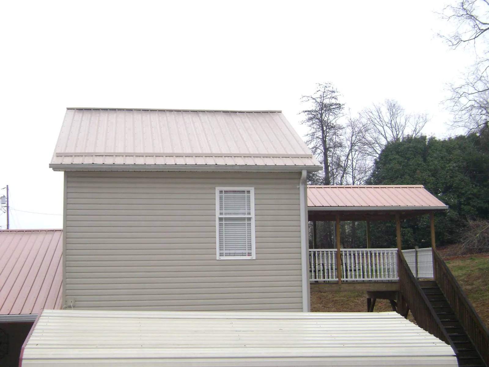 Tan metal roofs on a two story addition and attached porch, from a Roof Replacement job in Bath